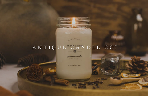 Large scented candle by Antique Candle Co on a table, creating a retro and cozy atmosphere.