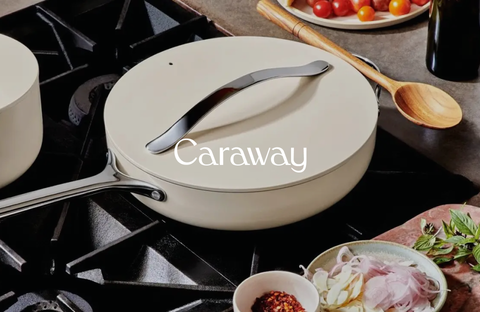 Ceramic skillet by Caraway on a modern, well-equipped stove surrounded by ingredients, ideal for healthy cooking.