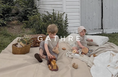 Two children sitting on an outdoor blanket by Gathre, perfect for outdoor play, combining style and functionality.