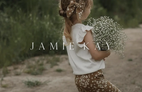 Child wearing a white cotton top and patterned pants by Jamie Kay in a natural setting, symbolizing comfort and elegance for children.