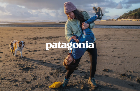 Person in outdoor Patagonia clothing playing with a dog on the beach, embodying the spirit of adventure and nature.