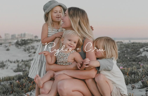 Mother and children dressed in matching outfits by Rylee + Cru in a sunny outdoor setting, evoking a gentle and family-friendly style.