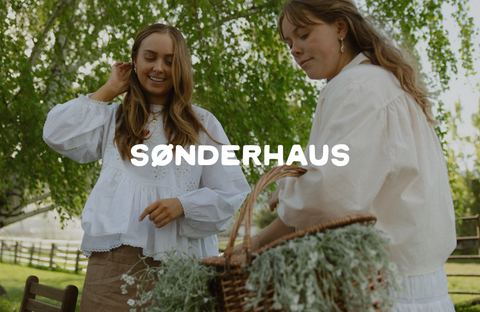 Two people in casual attire by Sønderhaus, wearing loose clothing in a natural setting, evoking a minimalist, bohemian, and eco-friendly style.